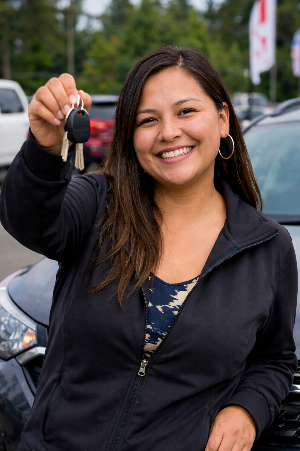 Happy customer holding keys to new vehicle on dealership lot