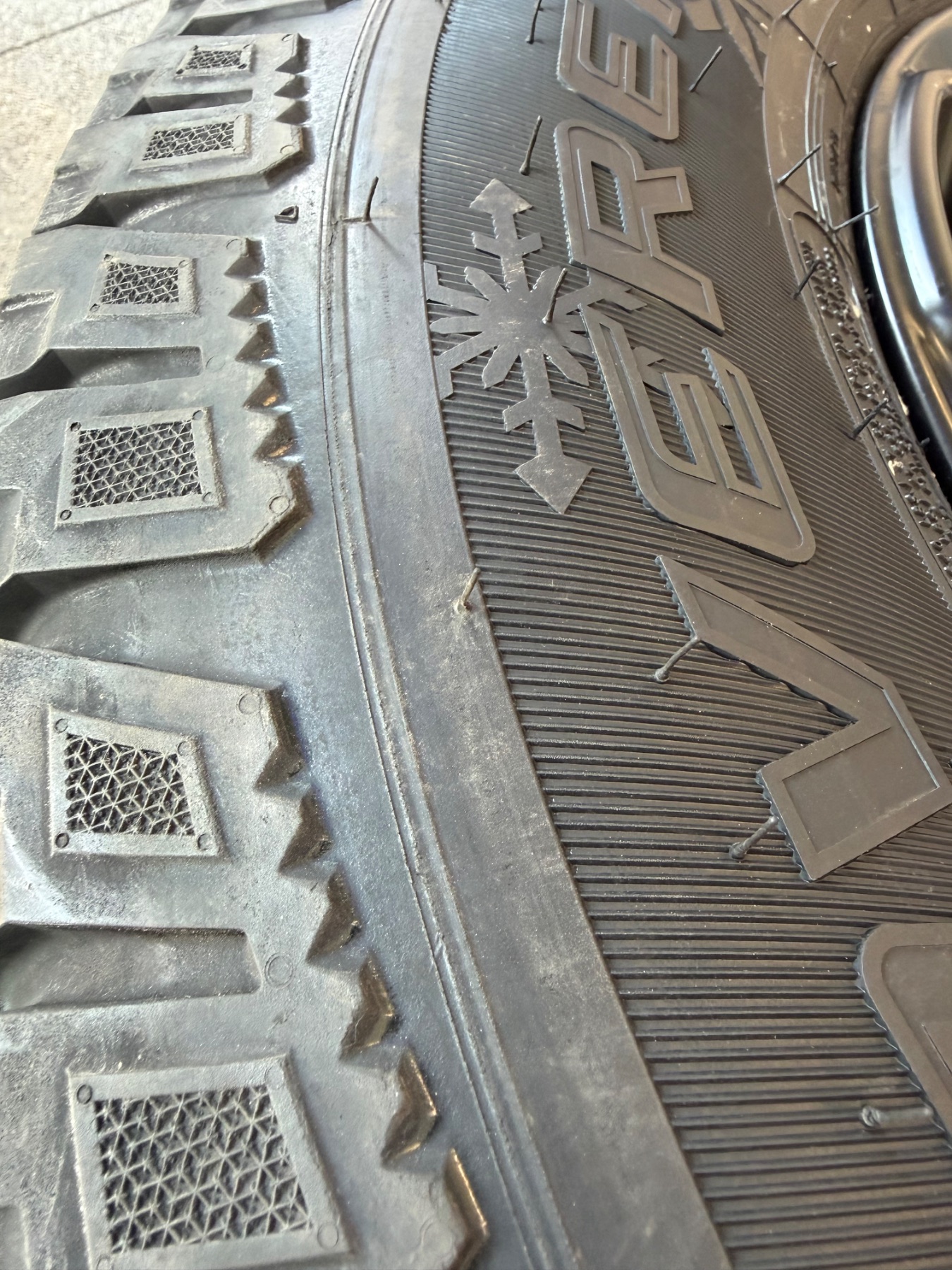 Winter tire tread close-up showing the three-peak mountain and snowflake symbol
