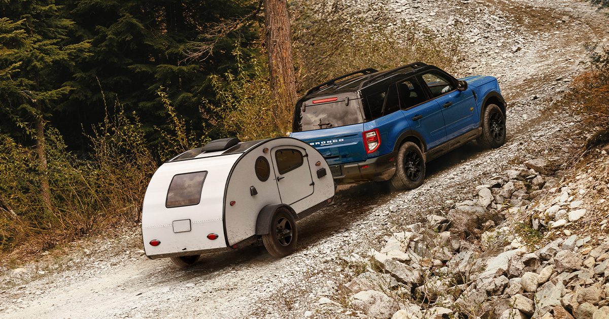 2026 Ford Bronco Sport towing a teardrop camper trailer up a gravel trail